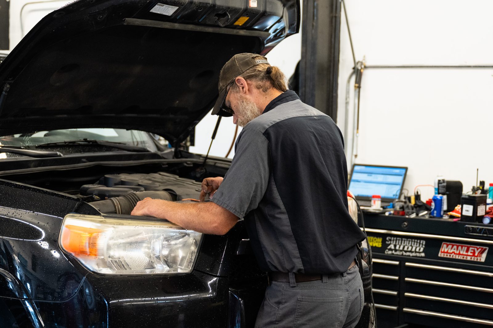Technician using a diagnostic laptop at the engine bay at Kalispell Alignment and Auto Repair