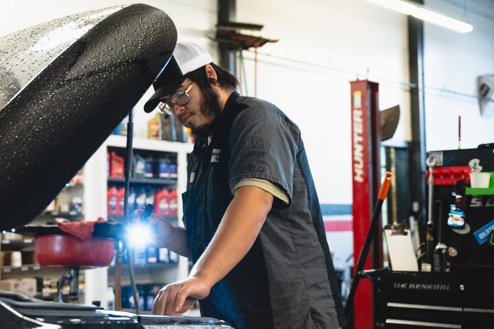 Technician checking under the hood with a flashlight