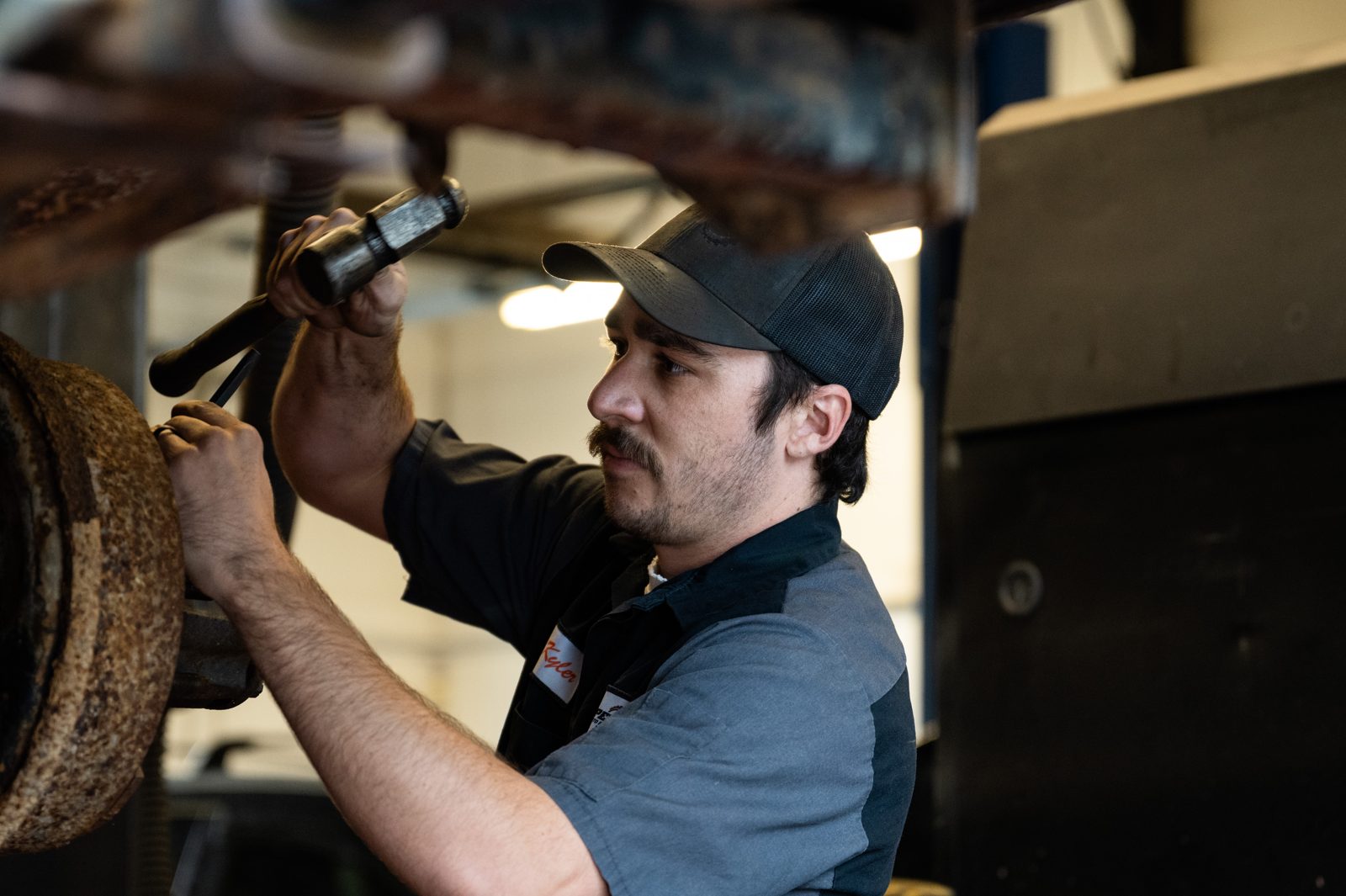 Technician inspecting the underside of a vehicle with a flashlight